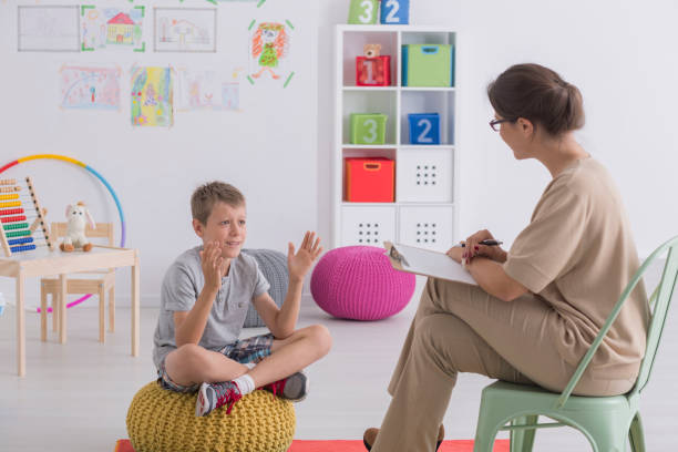 Child talking to therapist in colorful classroom with toys